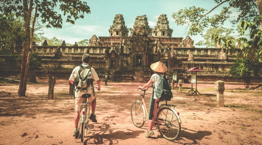 Biking past ancient temple ruins in Cambodia. Biking past ancient temple ruins in Cambodia.