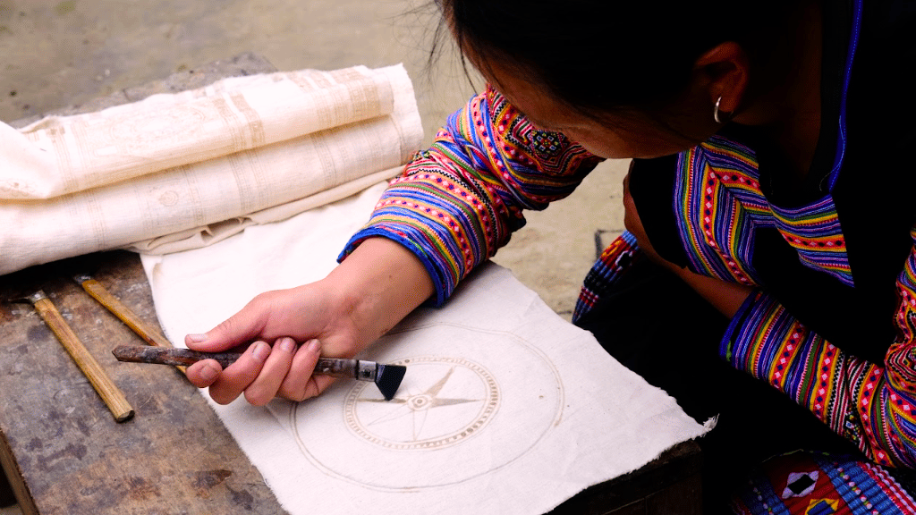 Hmong artisan practicing beeswax drawing on traditional fabric