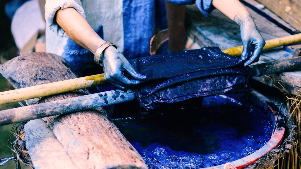 A Hmong woman dyes linen fabric with indigo before leaving it to air dry